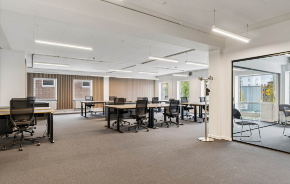 Open-plan office with multiple workstations and street-facing windows.